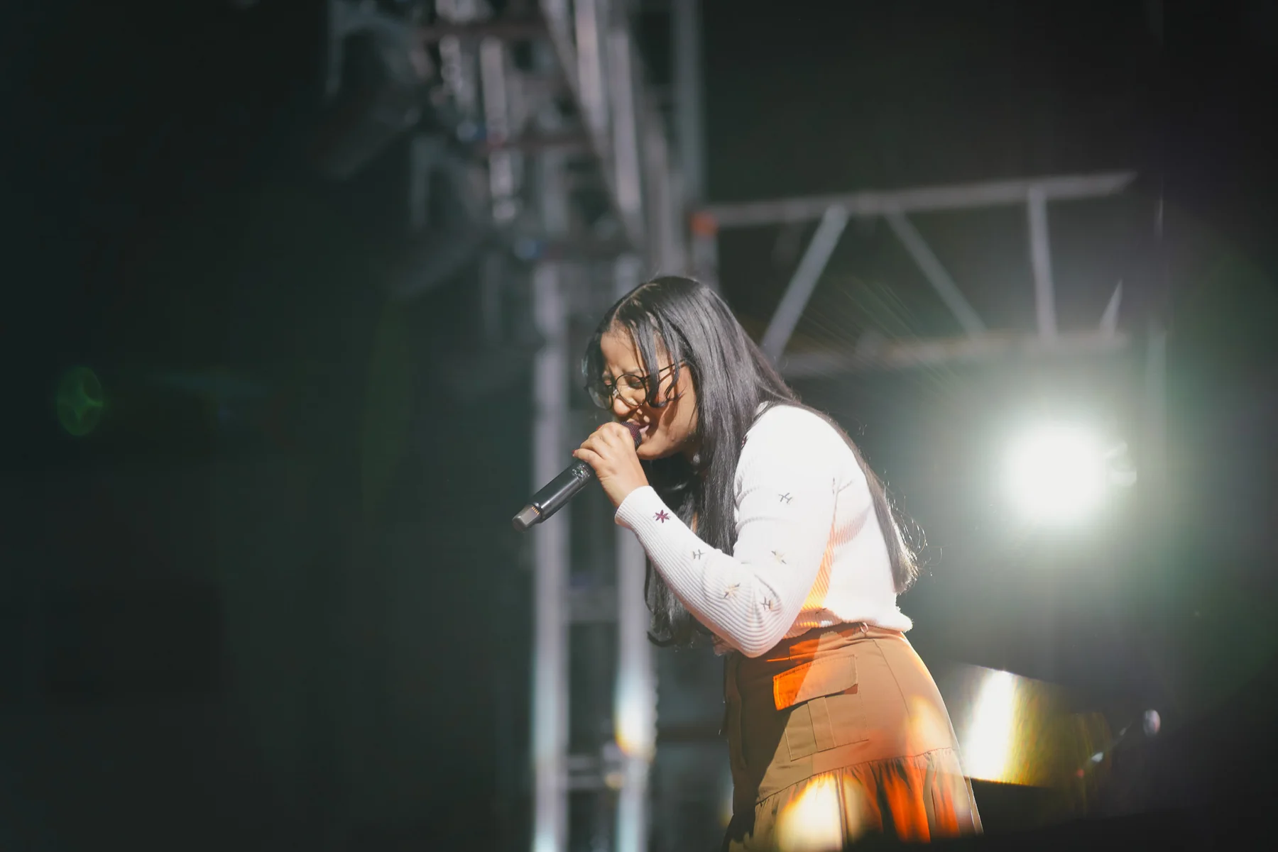 Vocalist performing under stage lighting at a live production