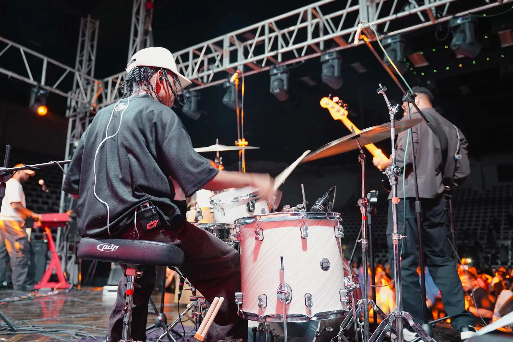 Drummer performing under stage lighting and overhead truss